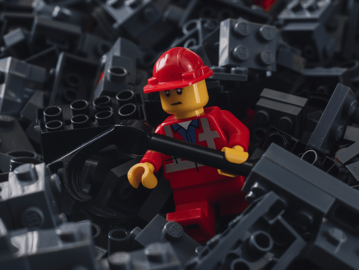 LEGO construction worker with shovel among bricks.