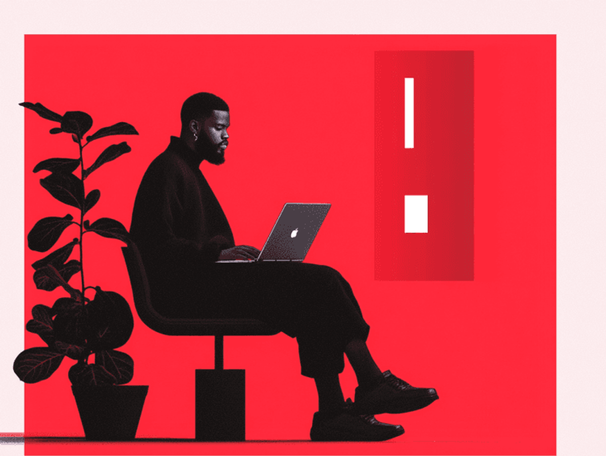 Person working on laptop with red background.