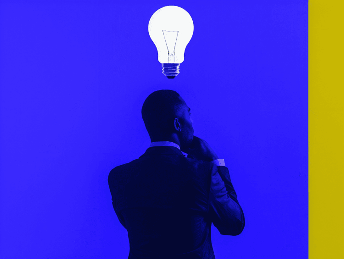 Man pondering with lightbulb overhead, blue background.
