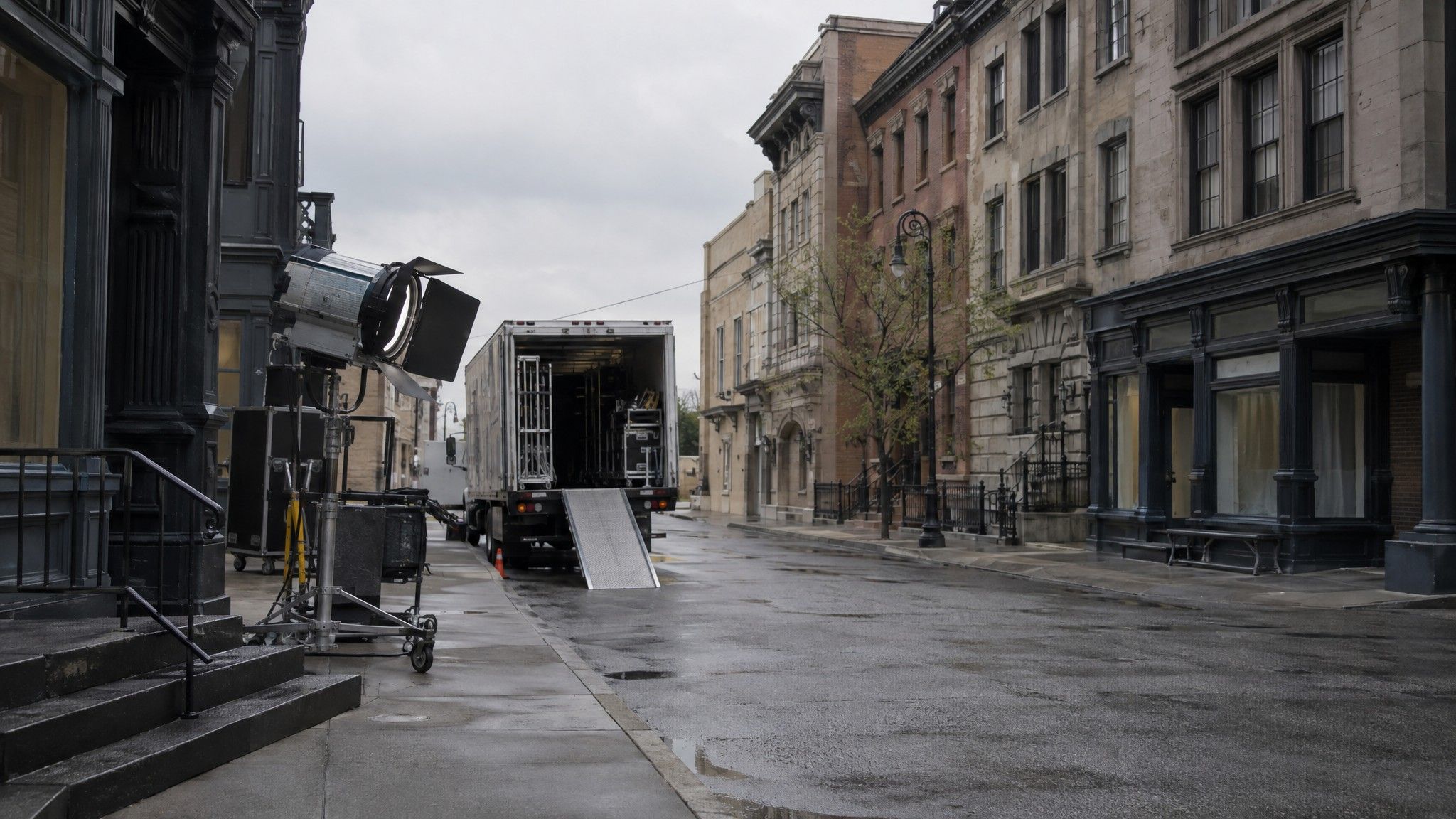 Film studio backlot street with facades and a parked lighting truck