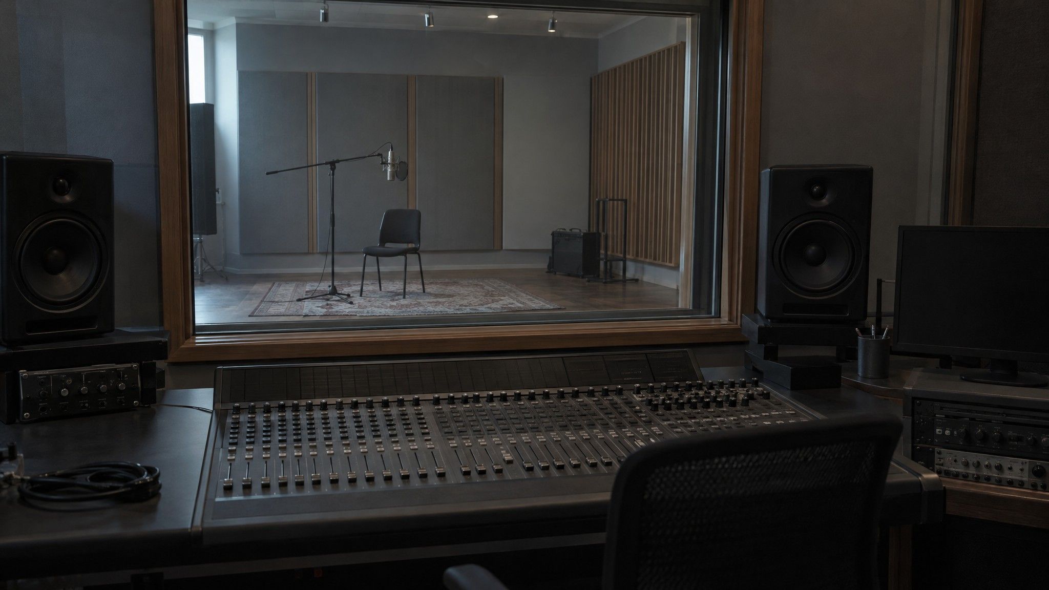 Control room with mixing desk looking into an empty studio