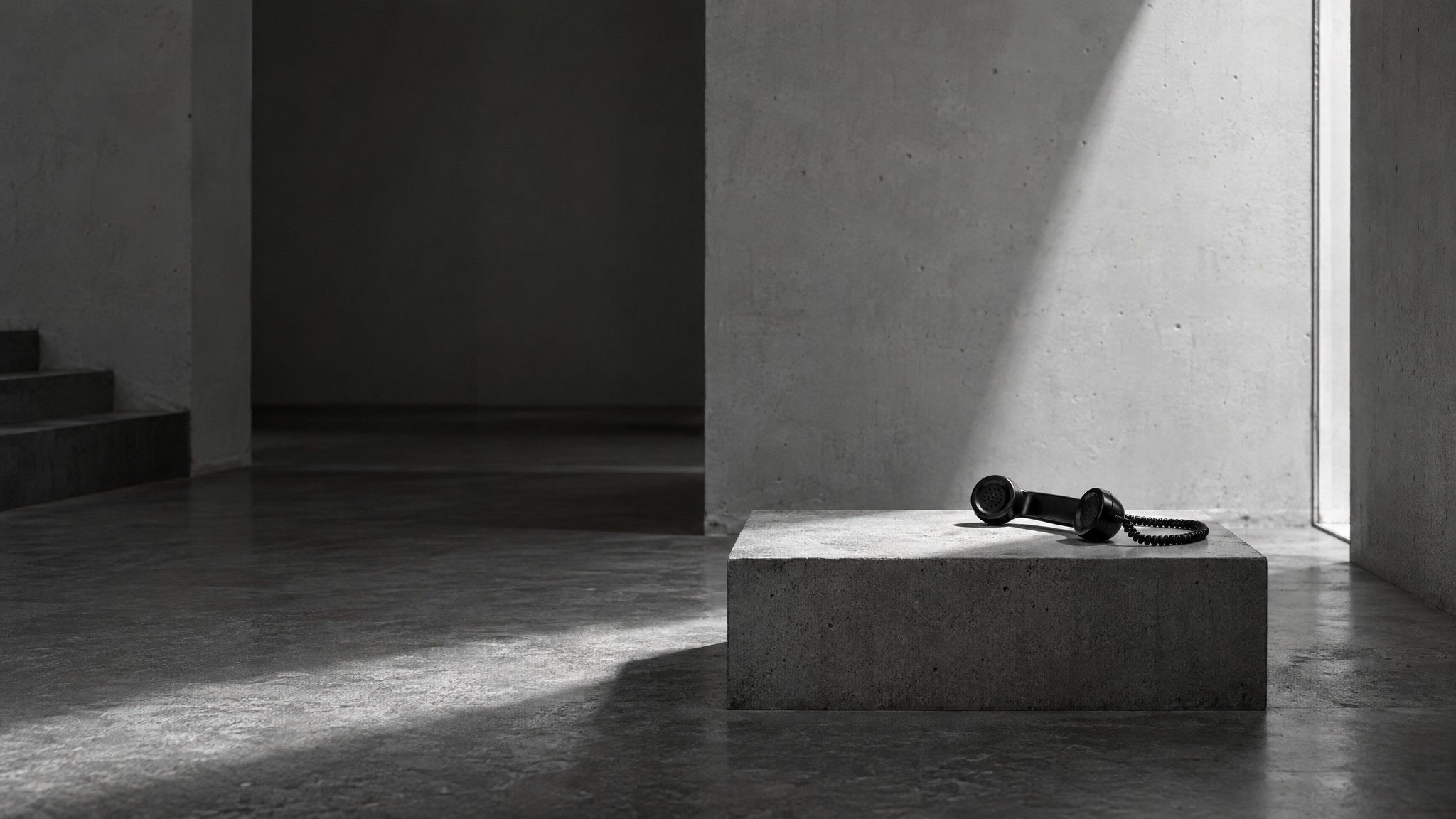 Telephone handset on a concrete plinth in a white concrete room