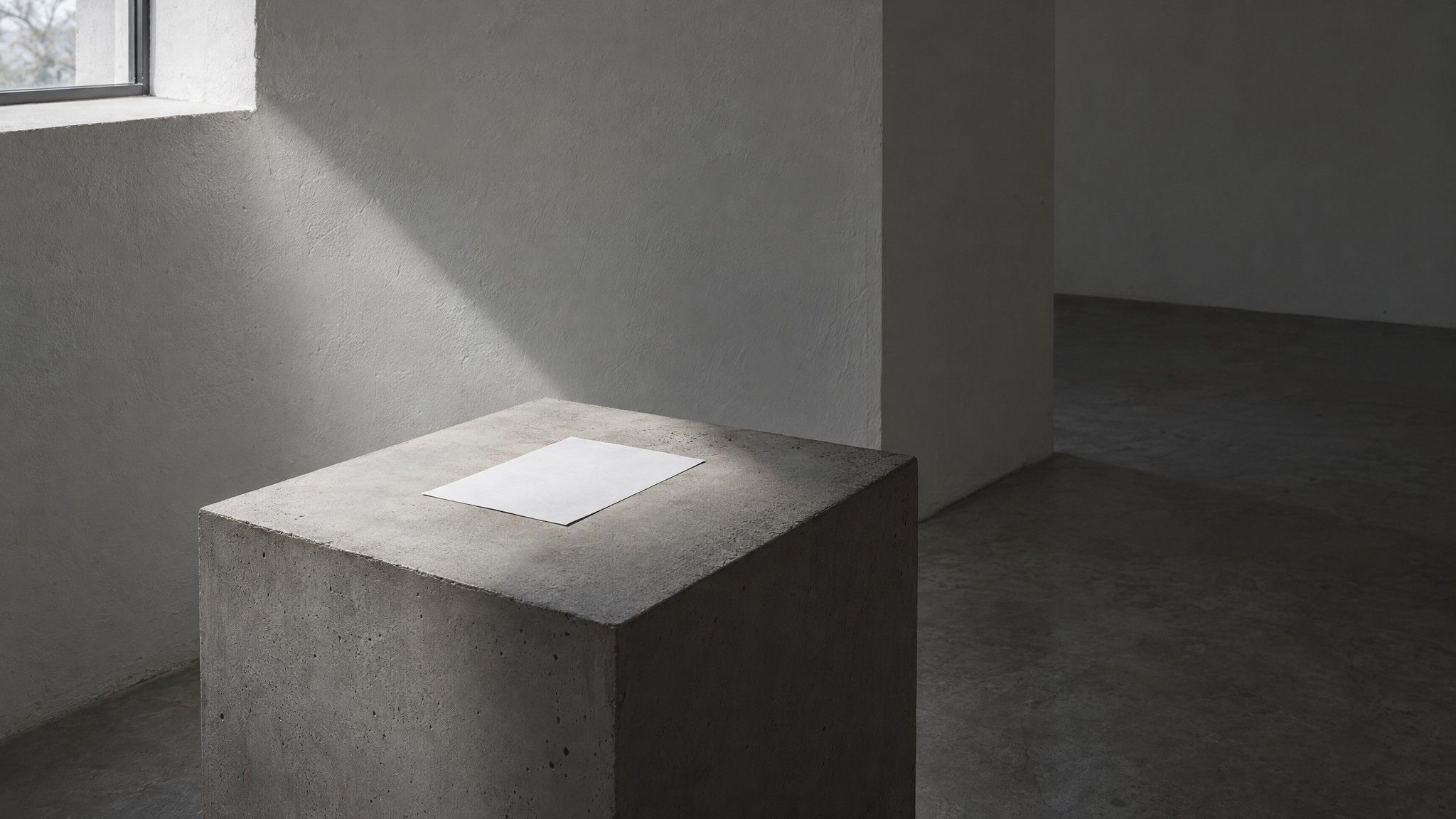 Blank sheet of paper on a concrete plinth in shadow