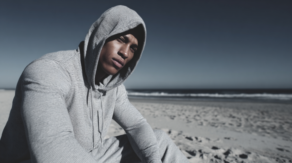 Man in hoodie on beach with ocean background