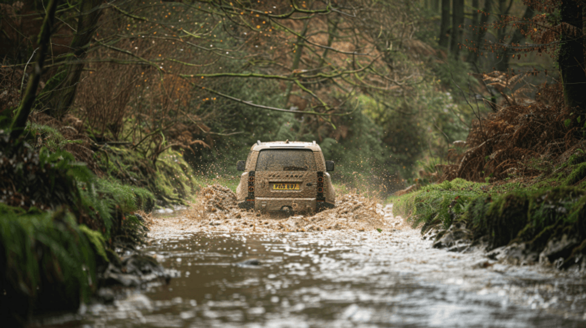 SUV driving through muddy forest stream