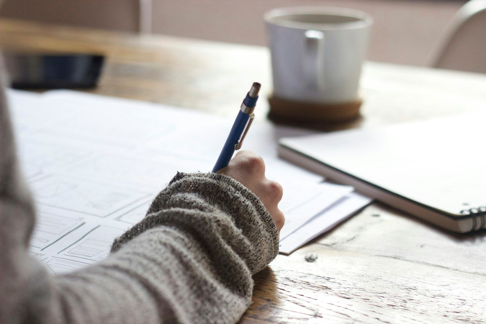 Person writing in a notebook at a clean workspace with natural light