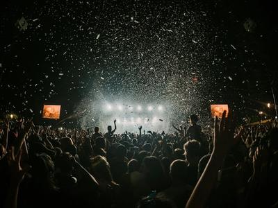 Large outdoor festival crowd with colorful stage lighting at dusk
