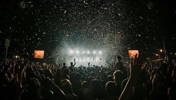 Large outdoor festival crowd with colorful stage lighting at dusk