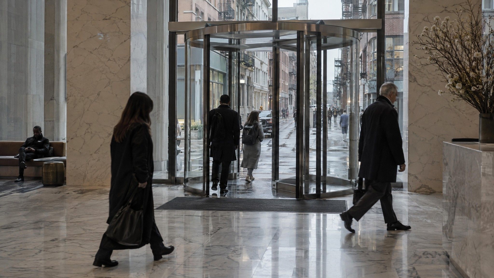 Marble lobby with a revolving door onto a side street of small studios
