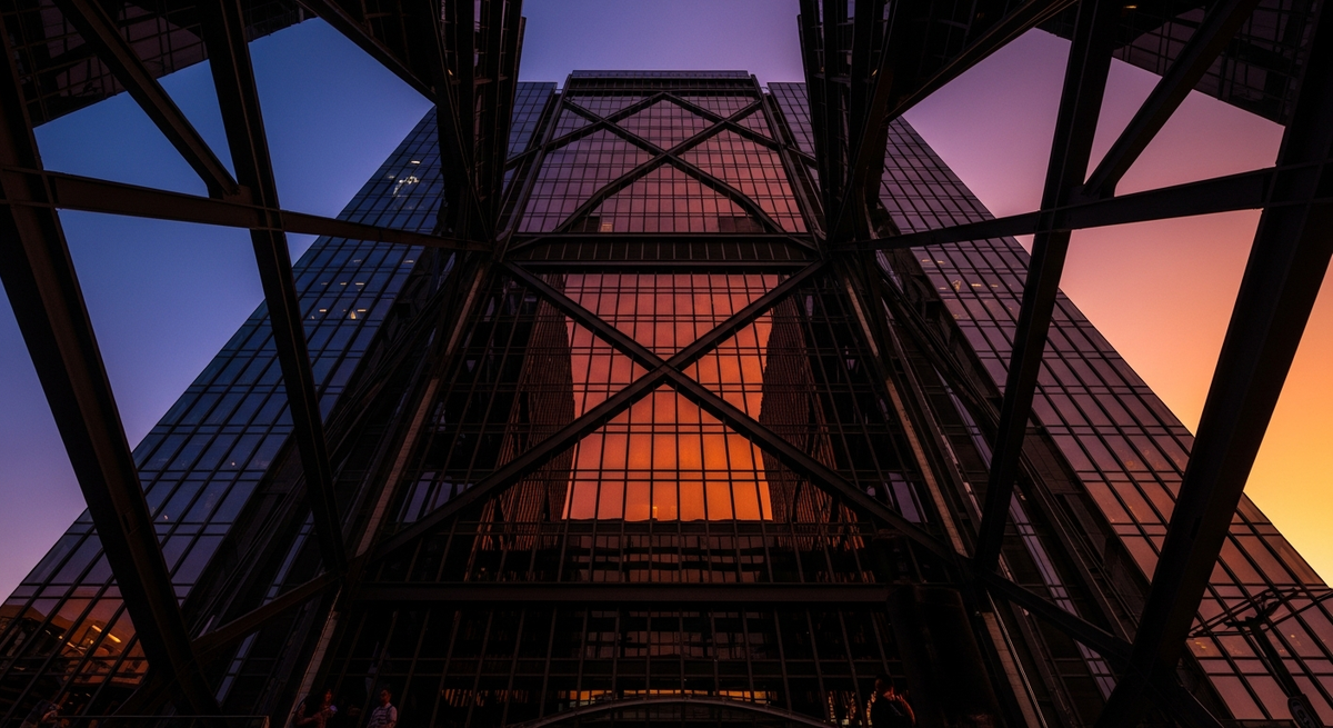Modern glass skyscraper reflecting vivid sunset with bold geometric architectural lines