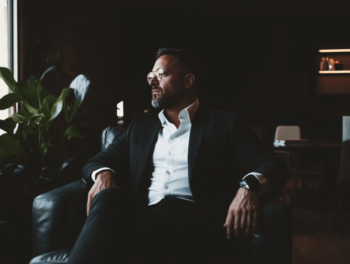 Man in suit sits in dark modern office
