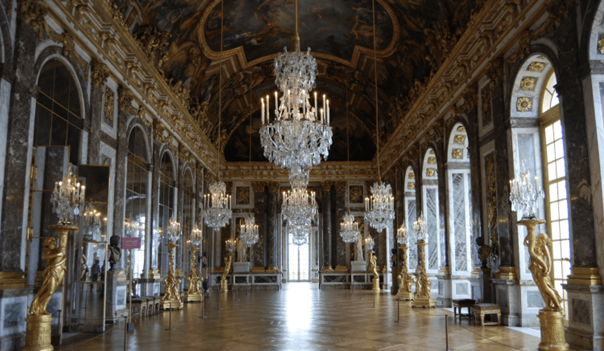 Opulent hall with chandeliers and mirrored walls.