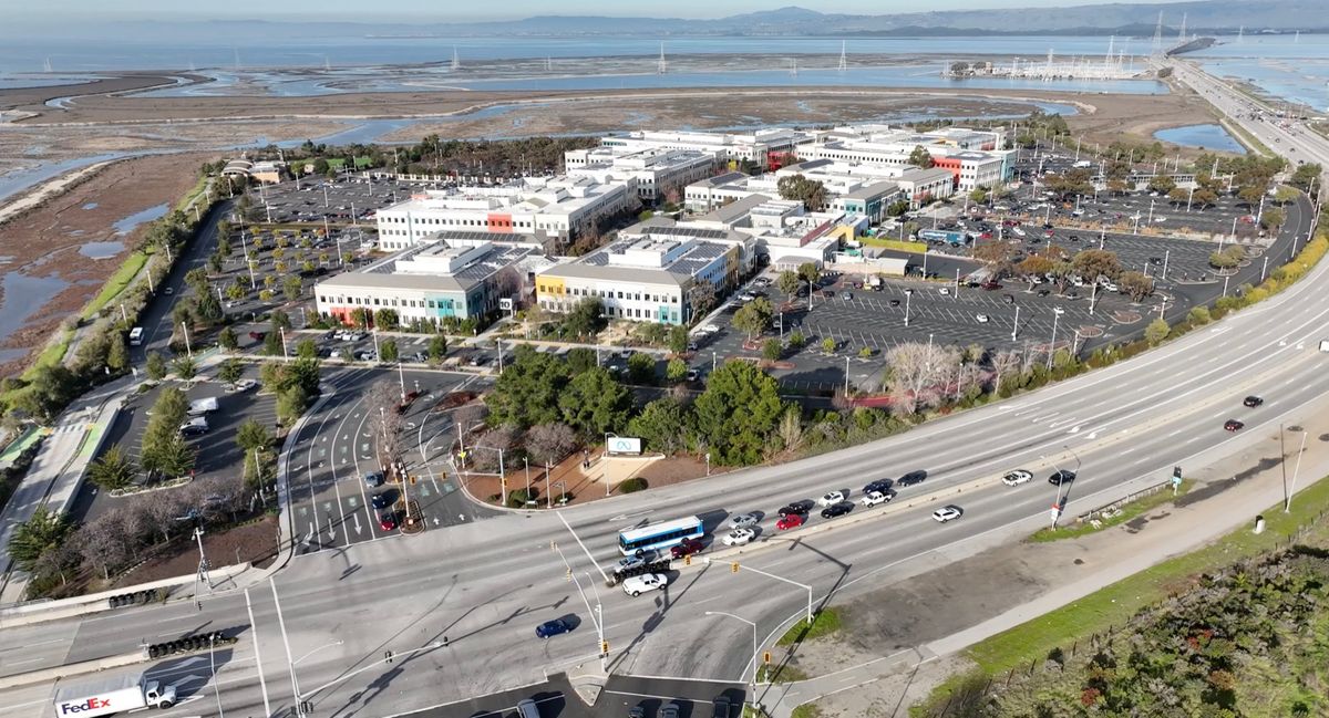 Aerial view of Meta's headquarters campus in Menlo Park beside a highway and the salt marshes of San Francisco Bay