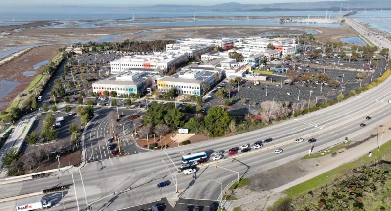 Aerial view of Meta's headquarters campus in Menlo Park beside a highway and the salt marshes of San Francisco Bay