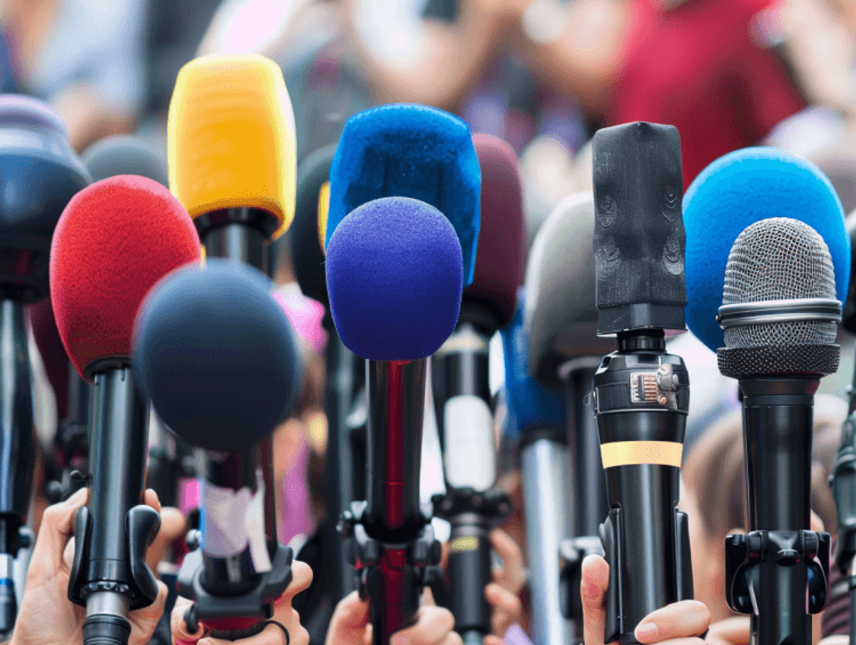 Colorful microphones held up at press conference.