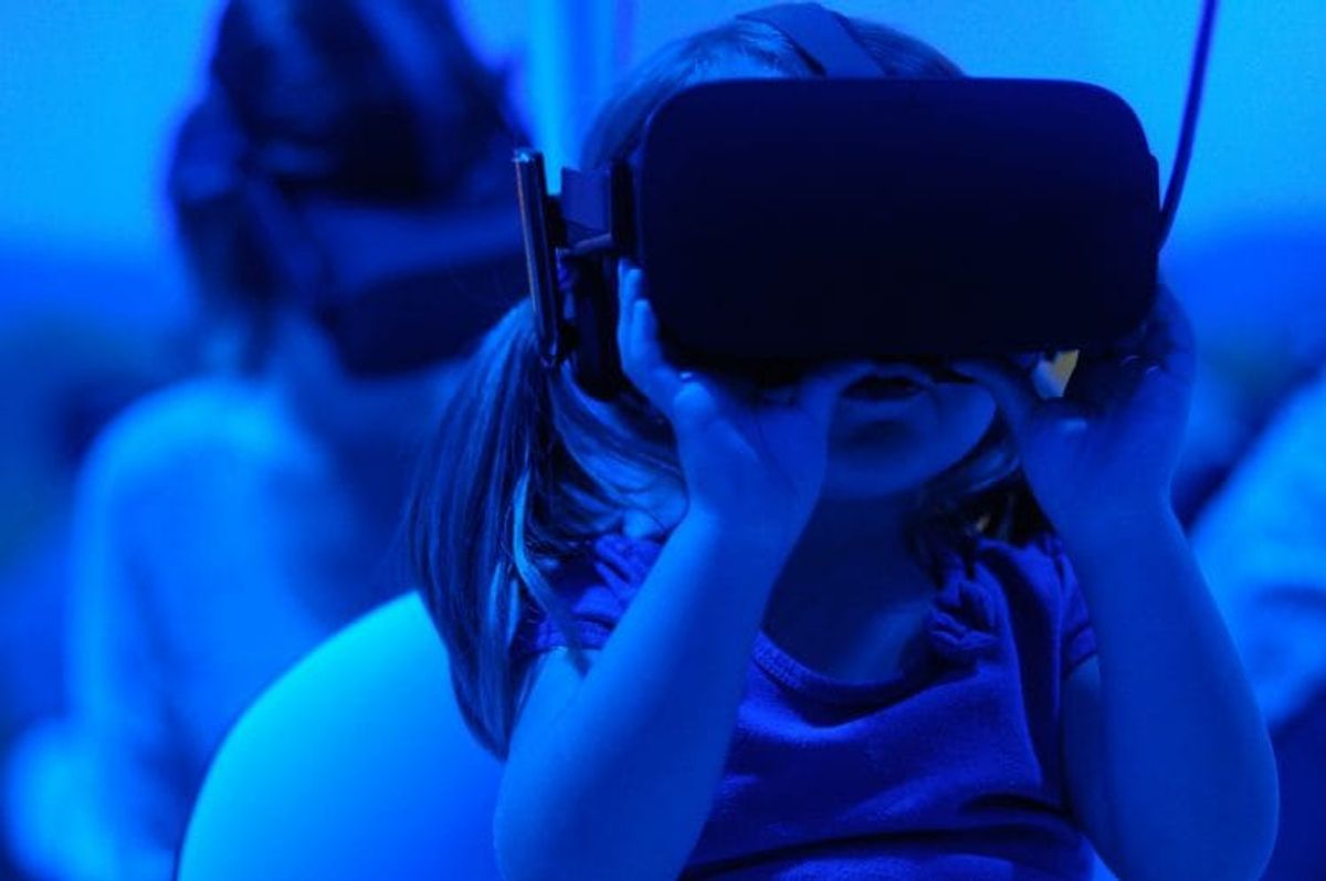 Child wearing virtual reality headset in blue light.