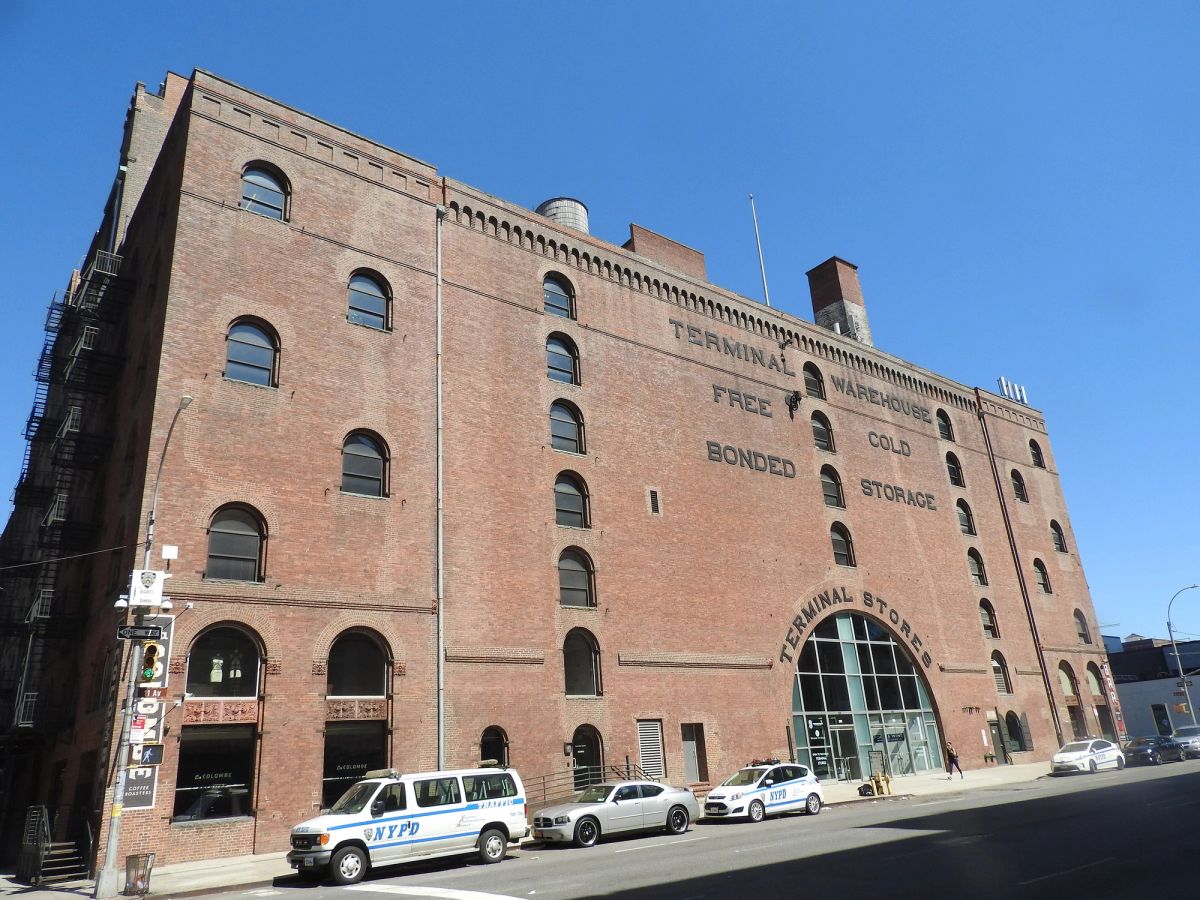 The Terminal Warehouse building in Chelsea, Manhattan, a long red-brick warehouse with arched windows, painted lettering reading Terminal Warehouse Free Bonded Cold Storage and a glass entrance under an arch marked Terminal Stores