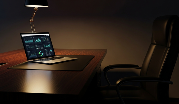 Executive desk with marketing analytics on laptop screen in dark moody corporate setting