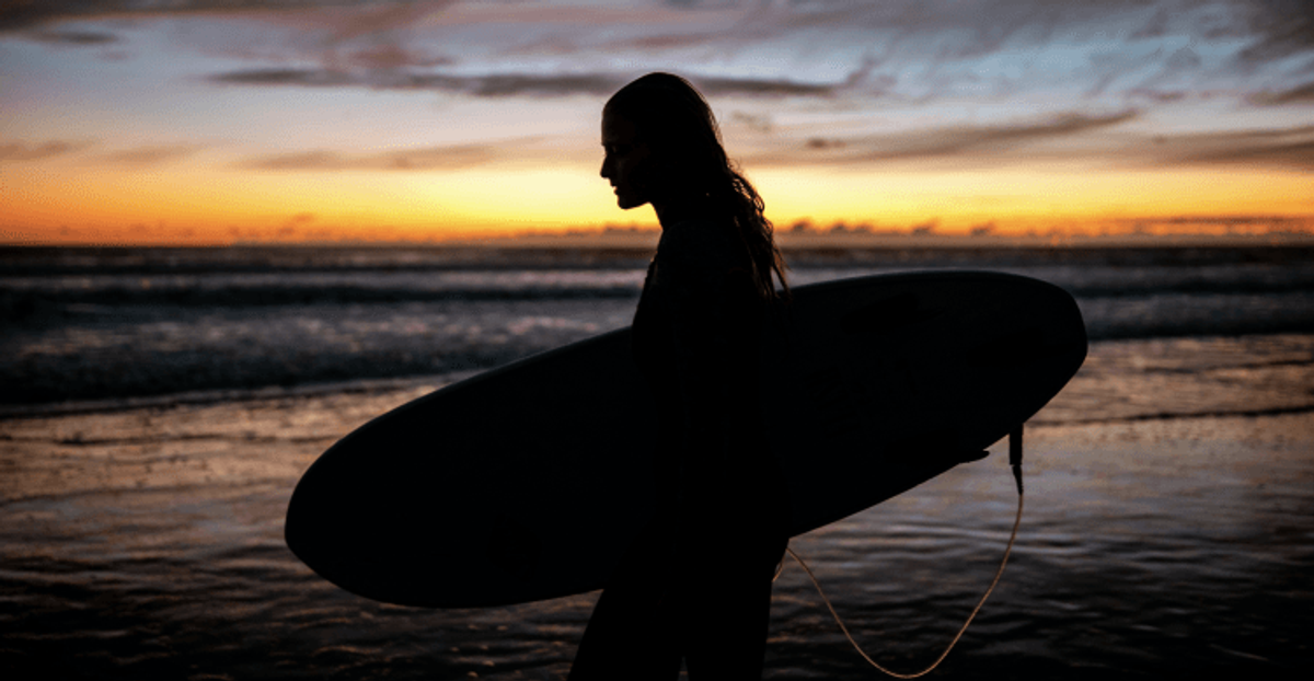 Silhouette of surfer at sunset beach