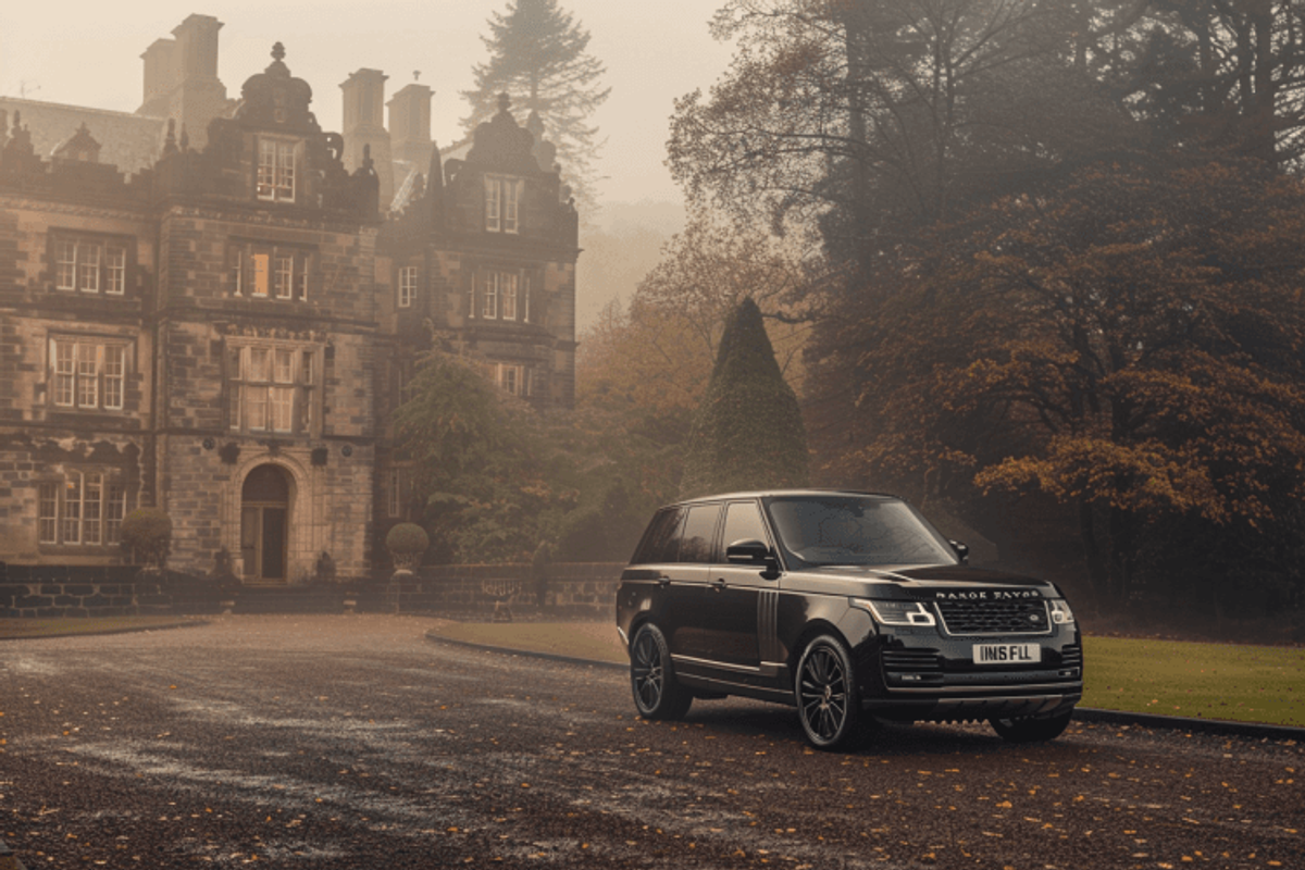 Luxury SUV parked outside historic mansion in fog.