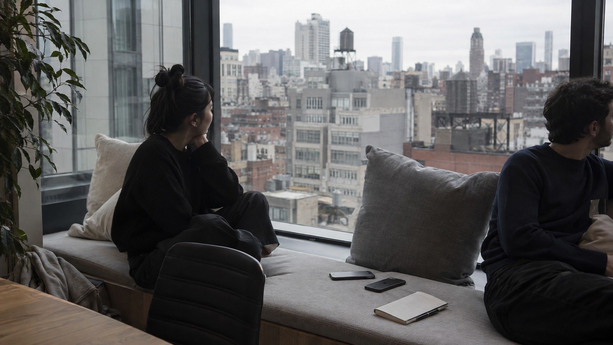 Window seat with phones face down and a notebook, rooftops outside