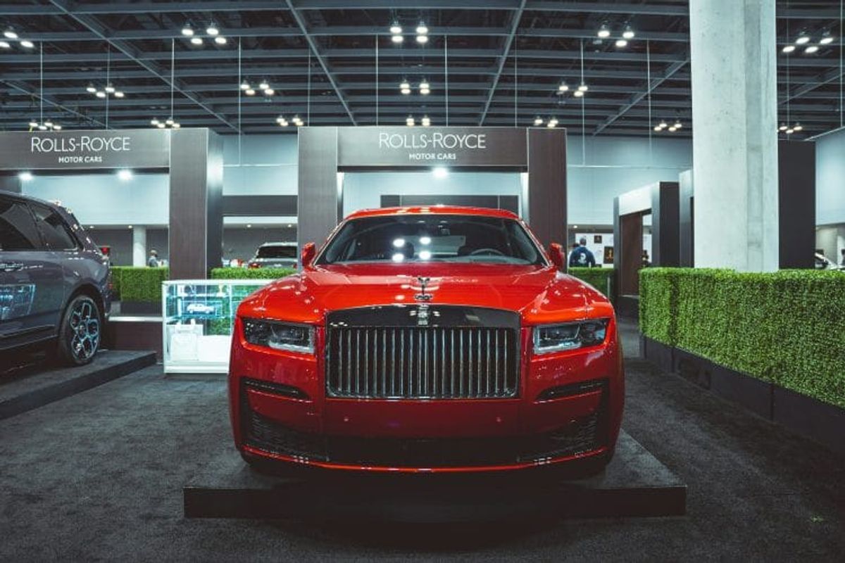 Red Rolls-Royce car at automotive show display.