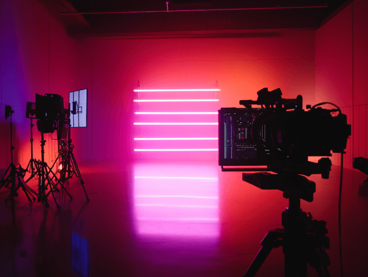 Film studio with vibrant pink lighting setup.