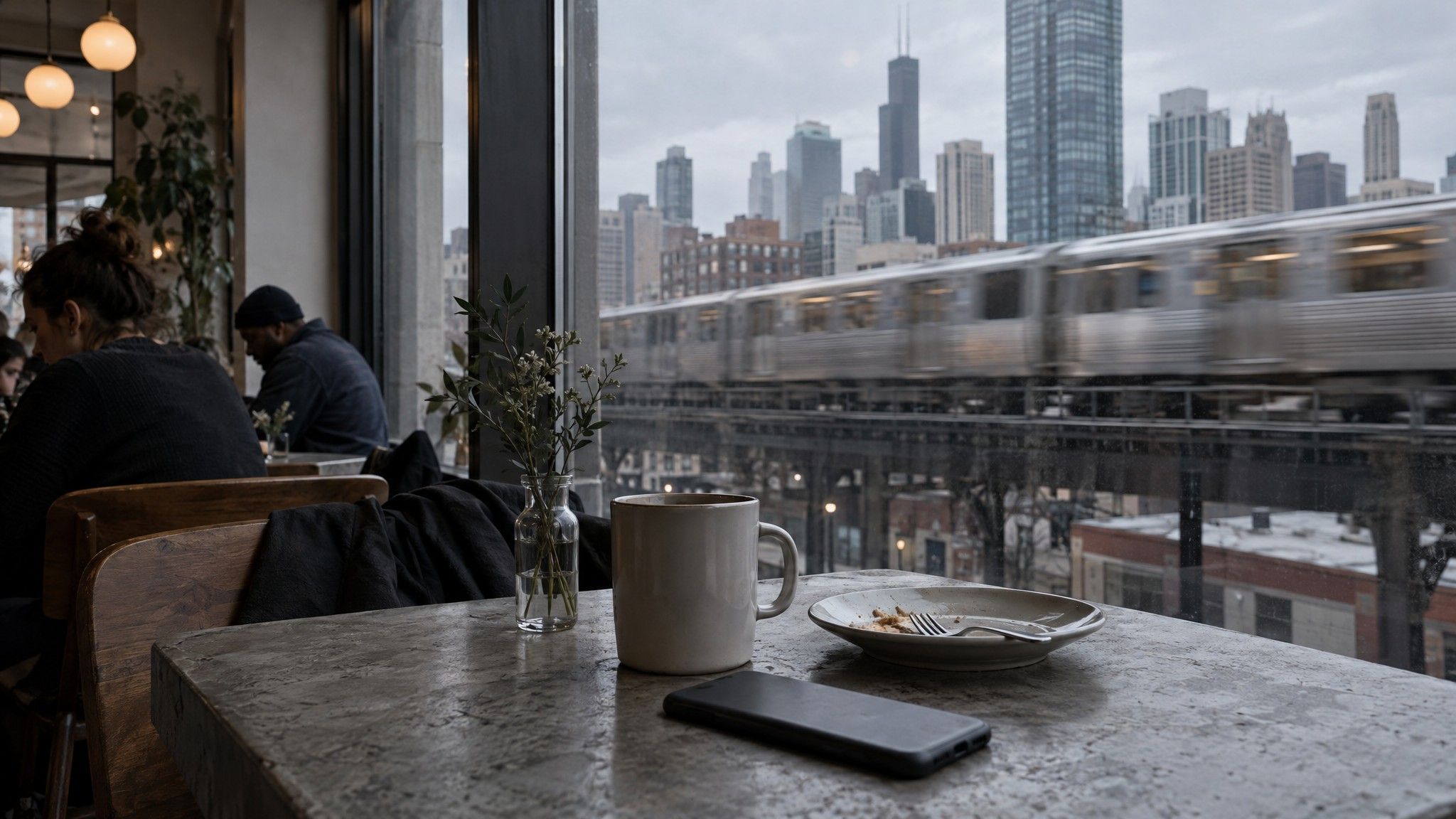 Phone screen-down on a concrete café table with a train passing outside