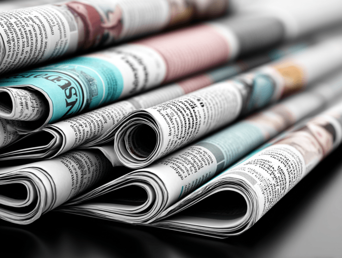 Stack of folded newspapers on black surface.