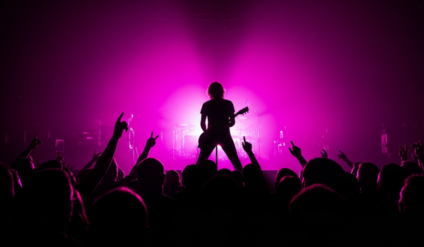 Concert performer silhouetted against vivid stage lights representing music promotion