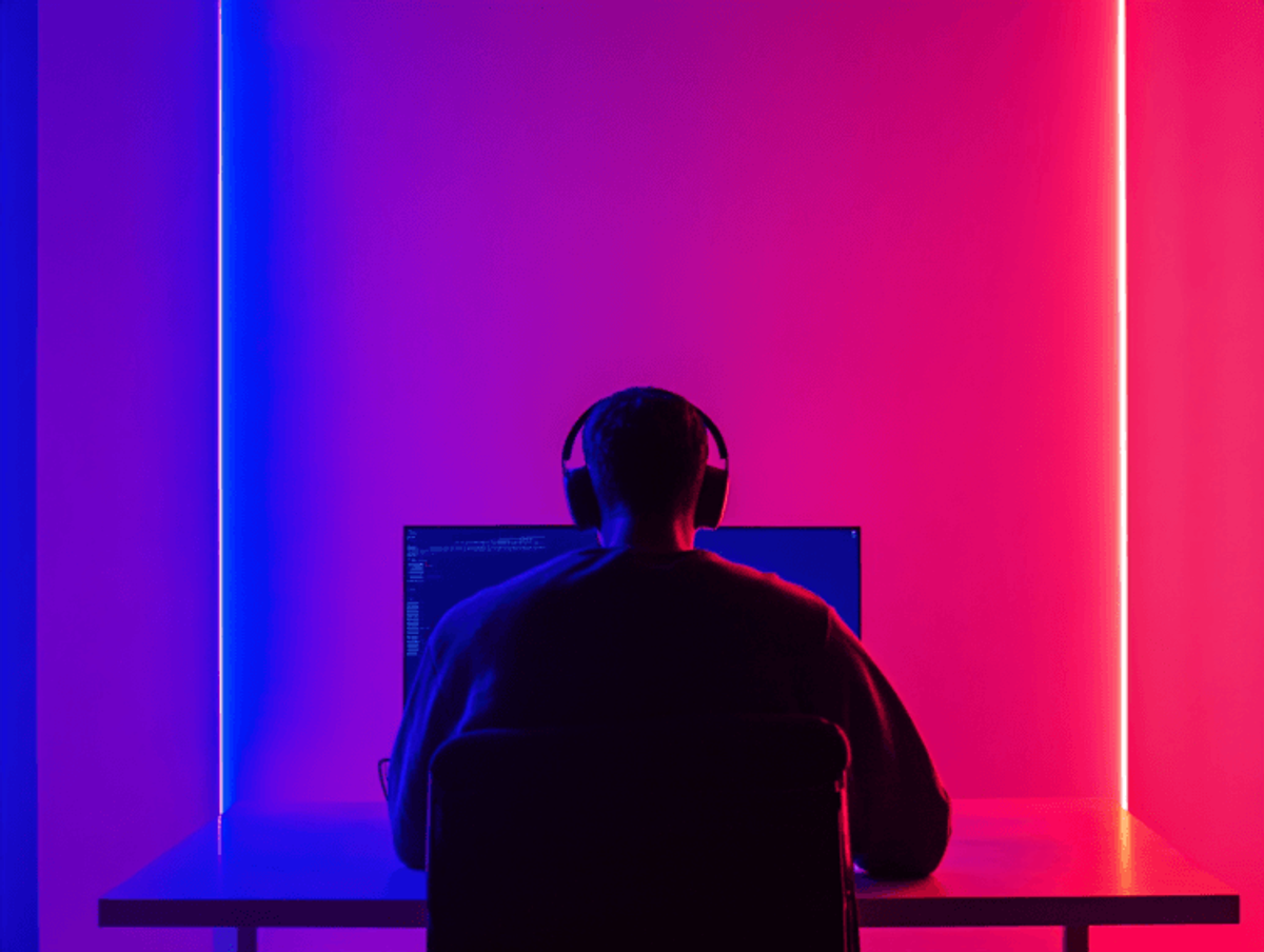 Person coding in neon-lit room