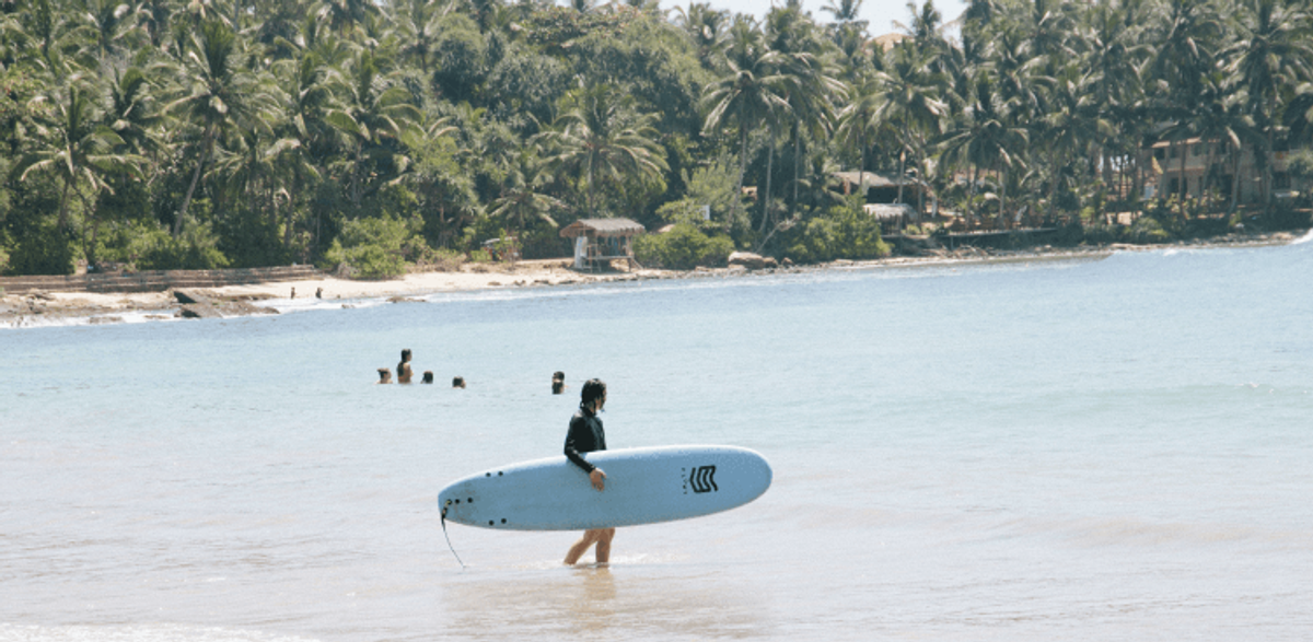 Surfer walking on a tropical beach.