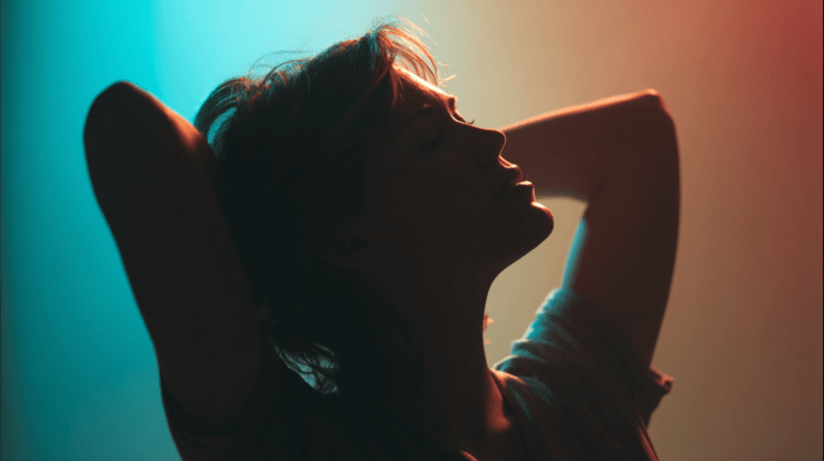 Silhouette of person under colorful lighting