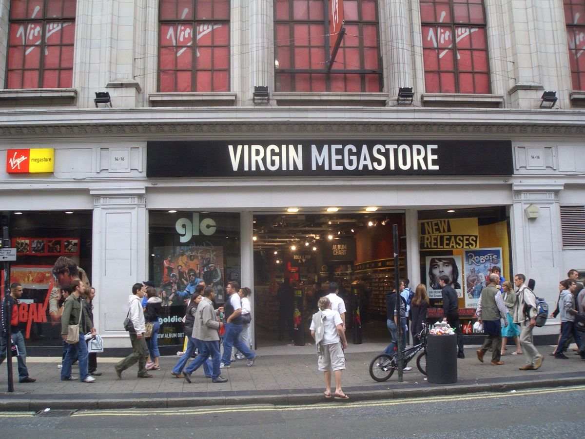 Front of the Virgin Megastore on Oxford Street with its black and white sign, red Virgin logos in the upper windows and shoppers walking past