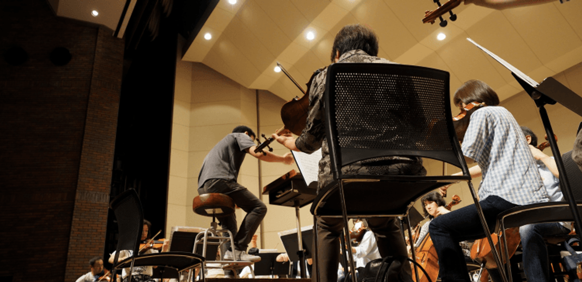 Orchestra rehearsal with conductor and string instruments.
