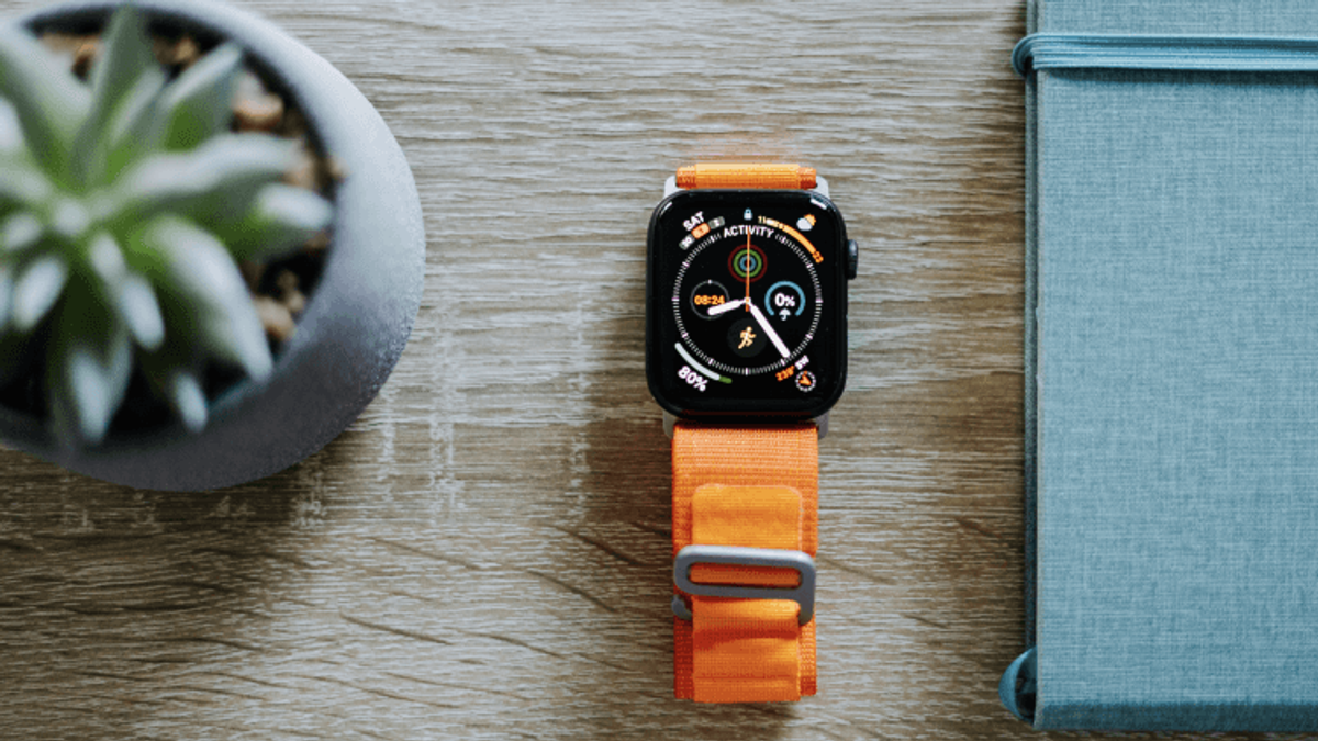 Smartwatch with orange strap on wooden surface.