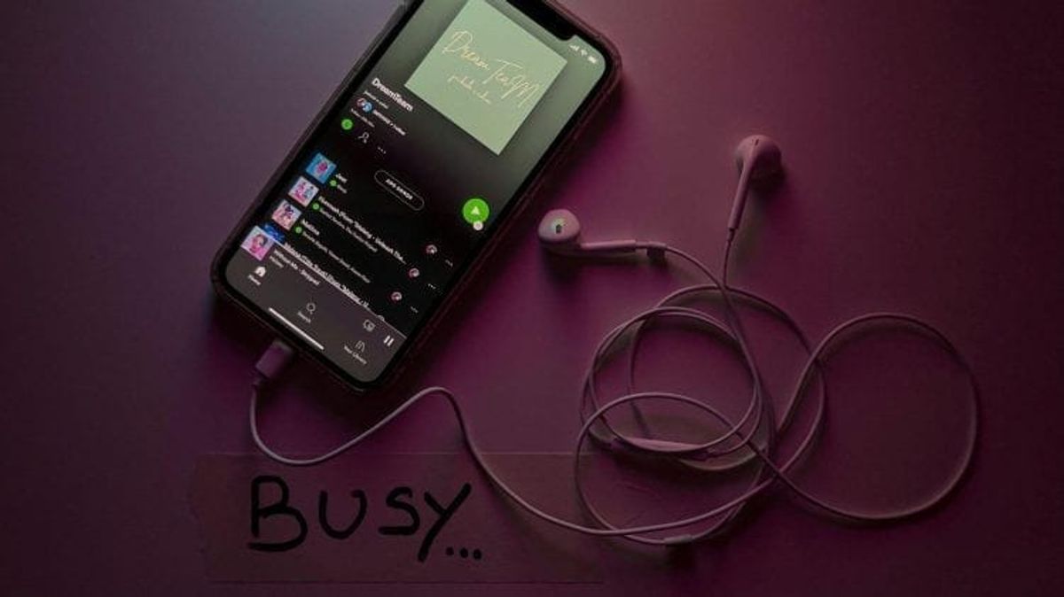 Phone with earphones playing music, text 'Busy.'