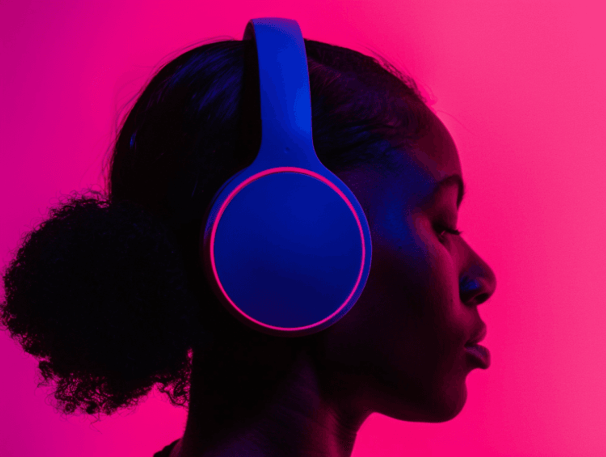 Person wearing blue headphones on pink background