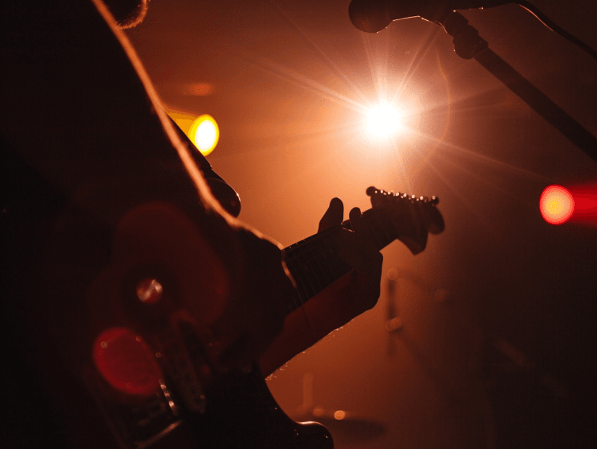 Guitarist performing under bright stage lights