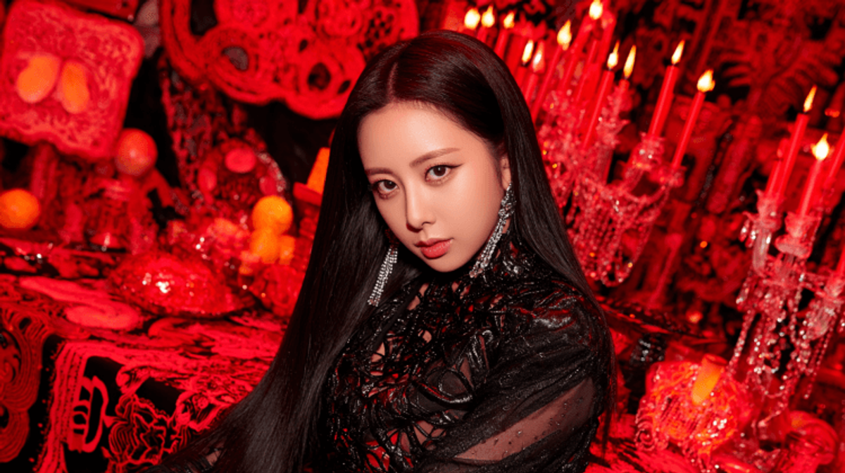 Person in dark lace attire, surrounded by red candles.