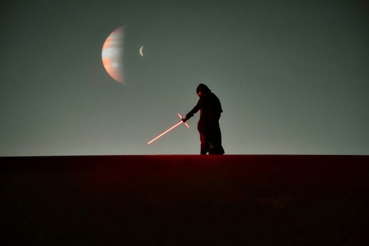 Silhouette with glowing sword, planets in background