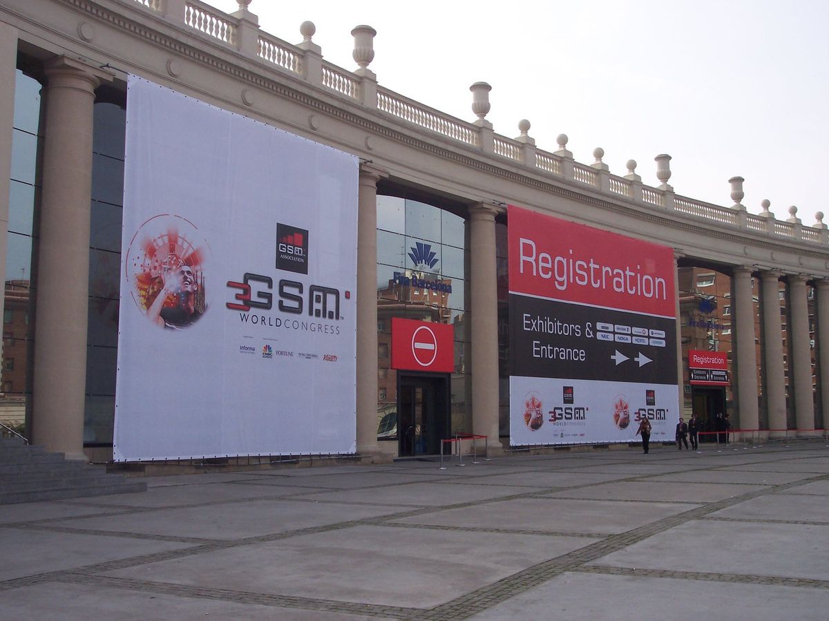The colonnaded front of a Fira de Barcelona hall hung with a giant 3GSM World Congress banner and a red Registration sign for exhibitors