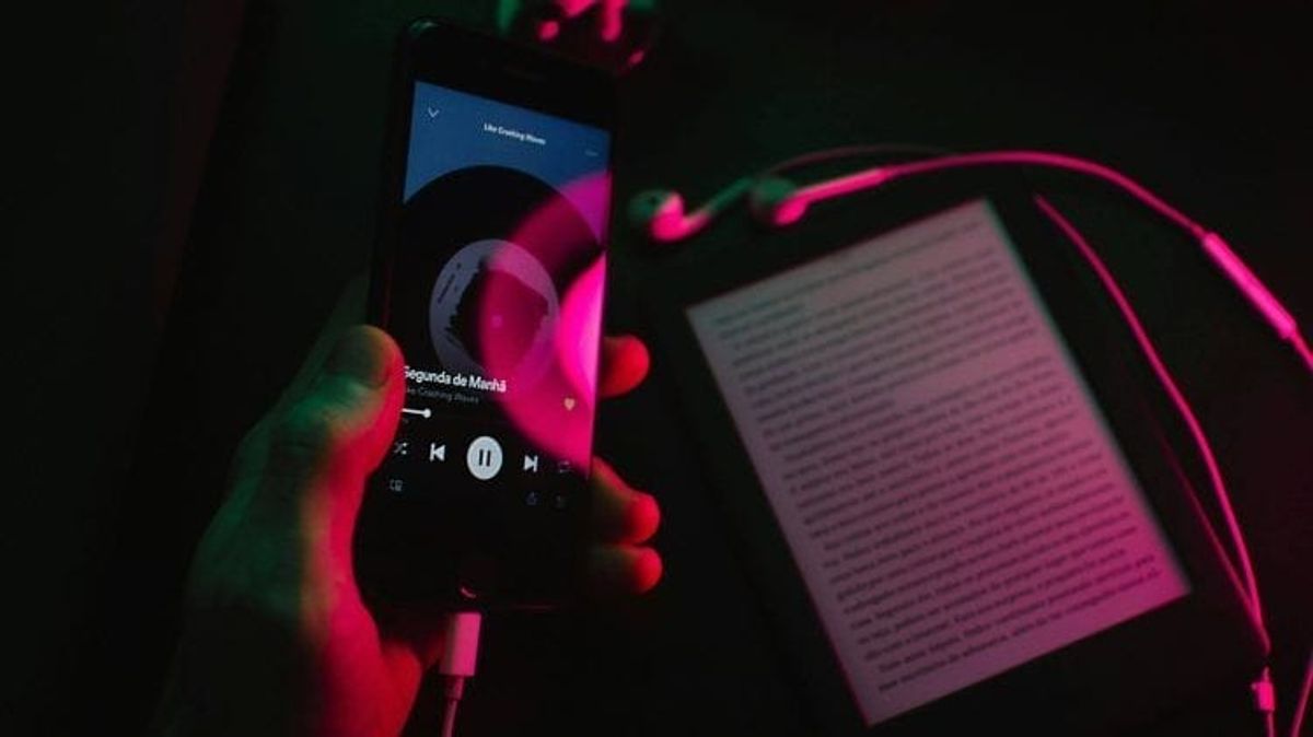 Smartphone streaming music next to an e-reader.