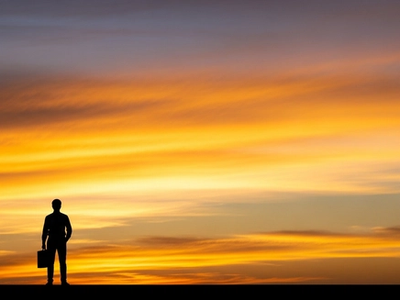 Bold silhouette of a confident professional against a vivid golden sunset sky