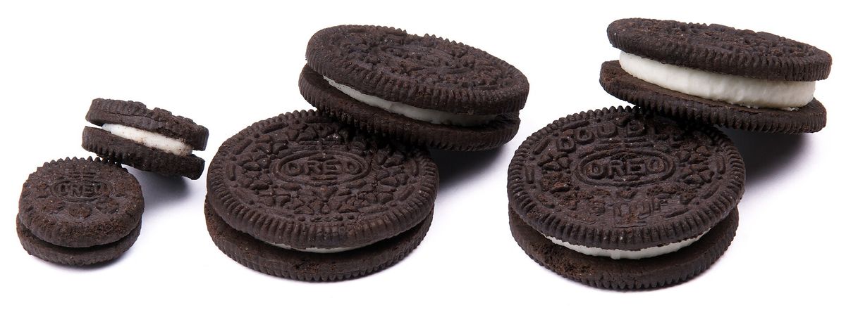 Pairs of Oreo cookies in three sizes on a white background: small Mini Oreos on the left, regular Oreos in the middle and Double Stuf Oreos with a thicker white filling on the right