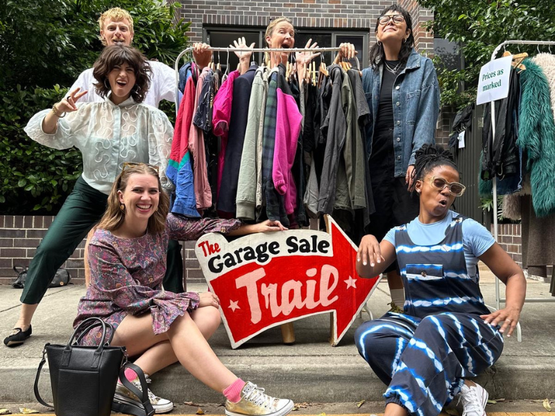 Six people posing with a clothing rack at a Garage Sale