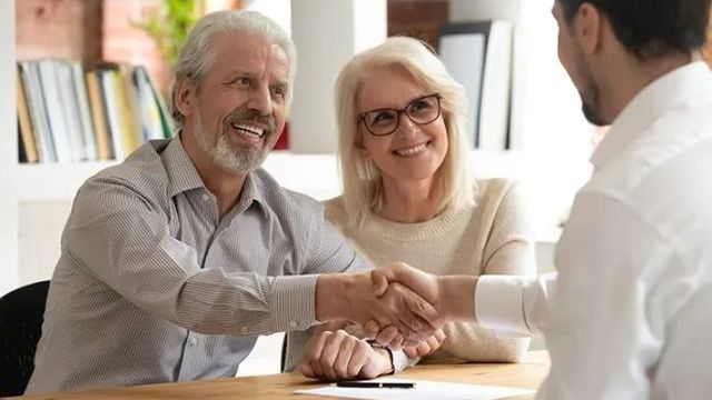 Retired Couple smiling shaking advisor hands