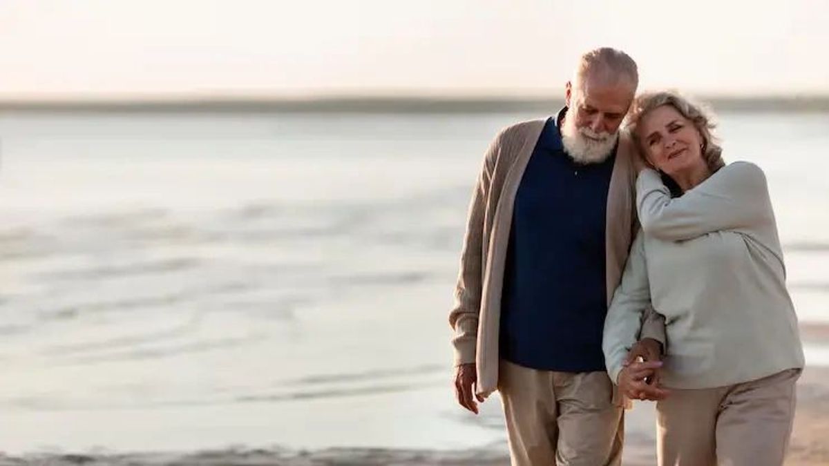 Retired couple holding hands on the beach
