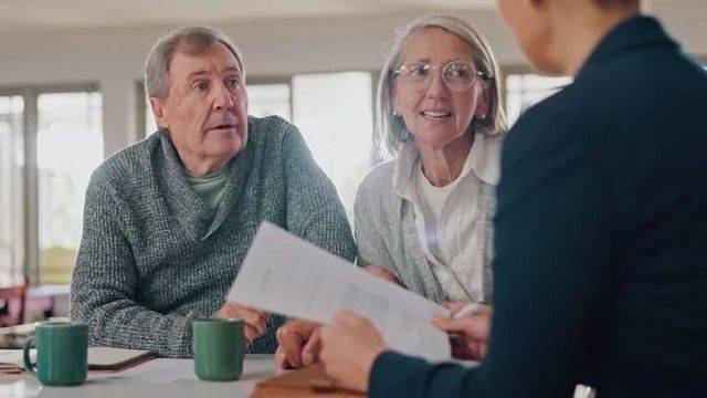 Retired couple meeting with a financial advisor to discuss retirement income, taxes, and safe withdrawal planning.