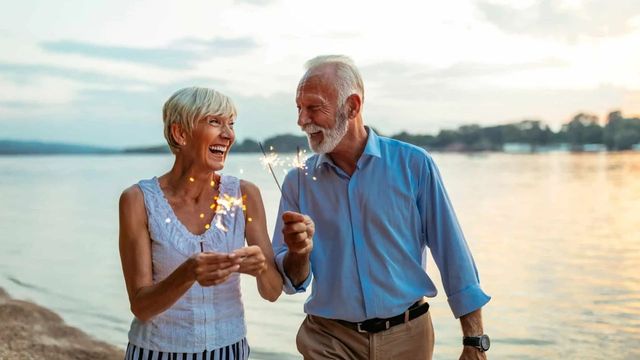 Retired couple by lake holding sparklers
